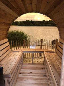 a dock with chairs and a view of a lake at Strandvilla met sauna in Westerhaar-Vriezenveensewijk