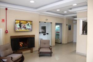 a waiting room with two chairs and a fireplace at Hotel Guaíba in Guaíba
