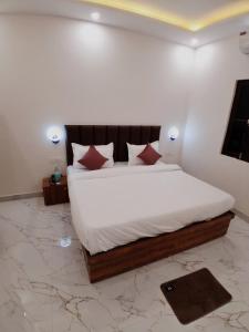 a bedroom with a large bed with white sheets and red pillows at Hotel Pantao Rishekesh in Rishīkesh