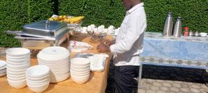 a man standing next to a table with white plates at Kagera Breeze Resort in Mbarara