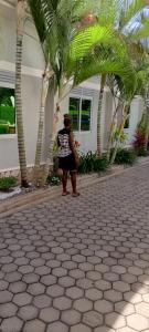 a woman standing in front of a house with palm trees at Kagera Breeze Resort in Mbarara