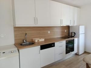 a kitchen with white cabinets and a sink at Apartman Ramljak in Prozor