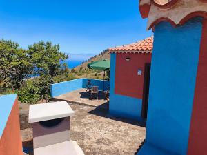 a blue and red house with a table and umbrella at Panchita in Garafía