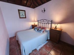 a bedroom with a white bed and a wooden nightstand at Panchita in Garafía +9 photos