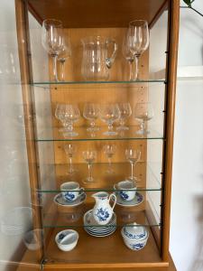 a glass cabinet with glasses and plates and cups at PENZION VLASTA in Zlín