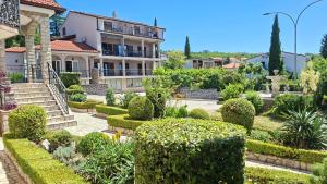 a garden in front of a house with bushes at Pansion Klaudija in Crikvenica