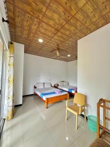 a room with two beds and a chair in it at Nandana Homestay in Udawalawe