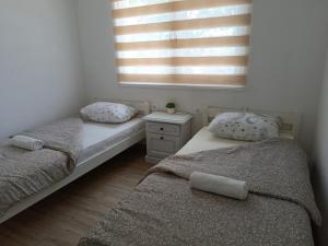 two twin beds in a room with a window at Apartman Ramljak in Prozor