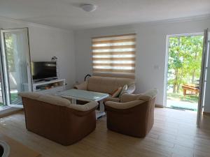 a living room with couches and a table and a tv at Apartman Ramljak in Prozor