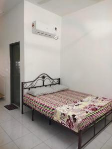 a bed in a room with a white wall at Angah Homestay in Kampong Chabang
