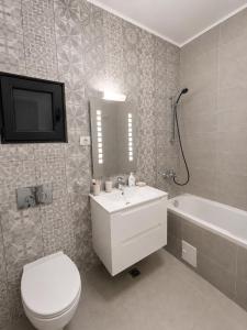 a bathroom with a toilet and a sink and a tv at Eqinox apartments in Mamaia Sat/Năvodari +15 photos