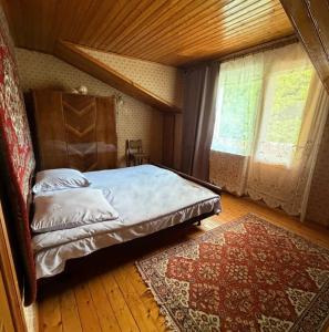 a bedroom with a bed and a window and a rug at Guest House Raisa in Dilijan