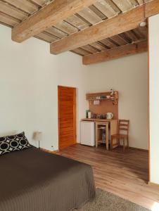 a bedroom with a bed and a desk with a kitchen at Viesu Nams Vilhelmīne in Līgatne