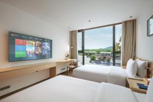 a hotel room with two beds and a flat screen tv at Jun hade on hillside in Hangzhou