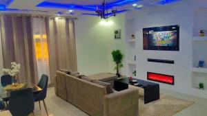 a living room with a couch and a tv on a wall at Apparemment PARC DES PRINCES in Yaoundé