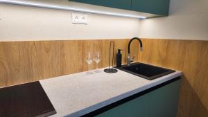 a kitchen counter with a sink and two wine glasses at Axiom Suites - Nova 4 in KoÅ¡ickÃ© KÃºpele