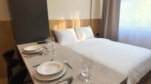 a hotel room with a bed and a table with plates and glasses at Axiom Suites - Nova 4 in KoÅ¡ickÃ© KÃºpele +5 photos