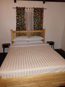 ein großes Bett in einem Schlafzimmer mit einem Holzrahmen in der Unterkunft Pula Re Accomodation in Savusavu + 8 Fotos