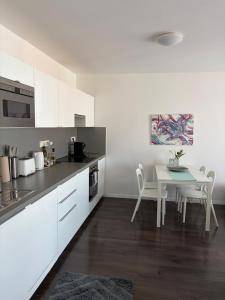 a kitchen with white cabinets and a table with chairs at Apartment Husova in Poděbrady