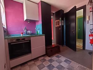 a kitchen with pink walls and a black at Solaris Guest House in Ciampino