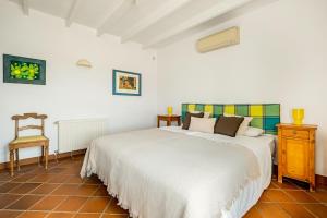 a bedroom with a large white bed and a chair at Villa Atréju in Cómpeta