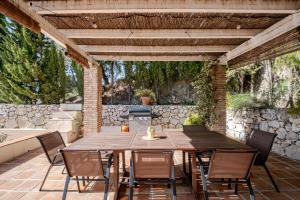 an outdoor patio with a wooden table and chairs at Villa Atréju in Cómpeta