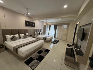 a bedroom with two beds and a flat screen tv at Hotel Prominent Town in Ahmedabad