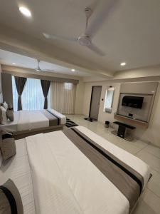 a hotel room with two beds and a flat screen tv at Hotel Prominent Town in Ahmedabad