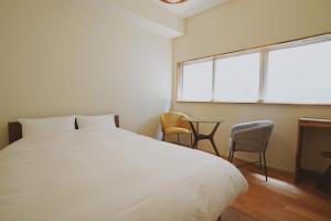 a bedroom with a bed and two chairs and a window at sunroom Hotel,Cafe,Bar in Miyazaki