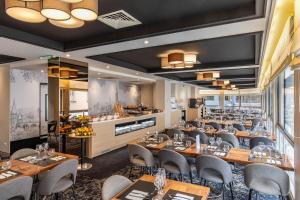 a restaurant with wooden tables and chairs and a bar at Helgon Hotel - Lourdes Pyrénées in Lourdes