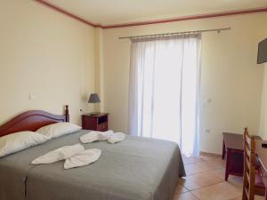 a bedroom with two towels on a bed with a window at Porto Fico Hotel in Vasiliki