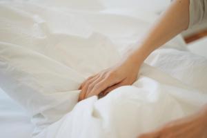 a woman laying on a bed with white sheets at sunroom Hotel,Cafe,Bar in Miyazaki