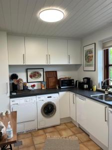 a kitchen with white cabinets and a washing machine at Driverhuset B&B in Grindsted