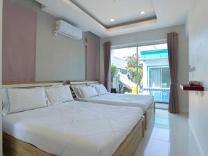 a bedroom with two beds and a large window at MUJI House Poolvilla Pattaya in Na Jomtien