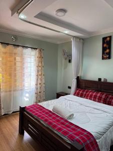 a bedroom with a large bed with a red plaid blanket at Villa maasai in Kimana