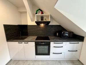 a kitchen with white cabinets and a black counter top at Teplice Apartments in Teplice