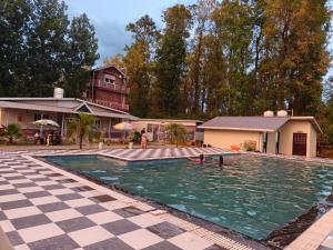 a swimming pool with two people in the water at Nature Nest Farms in Chūharpur
