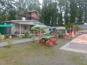 a table and chairs with umbrellas in front of a house at Nature Nest Farms in Chūharpur