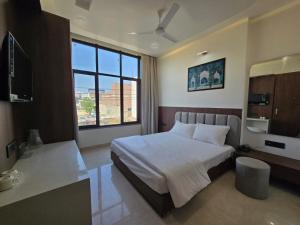 a bedroom with a bed and a large window at Shree Radha Raman Sarkar Dham in Vrindāvan