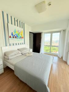 a white bedroom with a large bed and a window at trendy & Reliable Condo unit in Davao City +32 photos