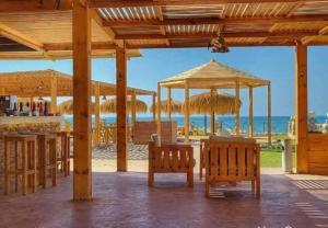 a pavilion with benches and umbrellas on the beach at Halaشاليه in Ras Sedr +16 photos