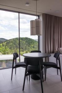 a dining room with a table and chairs and a large window at Vershky Villas Верховина in Verkhovyna