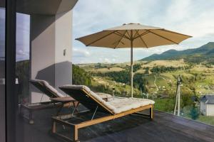 a couple of chairs and an umbrella on a deck at Vershky Villas Верховина in Verkhovyna