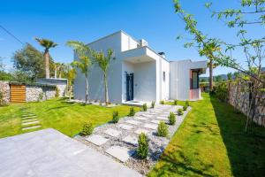 a backyard with a white house and a lawn at Villa Palma 2 in Beyobası