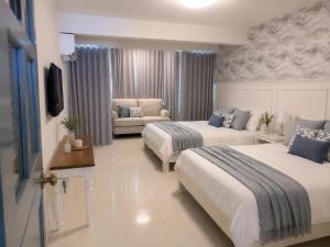a hotel room with two beds and a couch at บ้านเคียงคลื่น in Cha Am