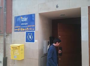 a man walking into a building with a sign at Albergue Izar in Viana