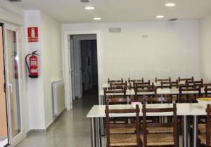 a room full of tables and chairs with a fire extinguisher at Albergue Izar in Viana