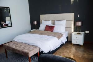 a bedroom with a large bed with white sheets and red pillows at Torriam Apartments in Chongwe