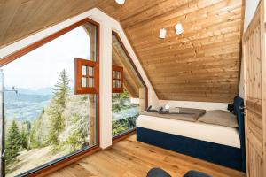 a bed in a room with a large window at Frauenalmresort - Chalets in Sankt Lorenzen ob Murau