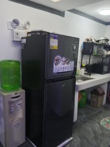 a black refrigerator in a kitchen next to a sink at Su Staycation Minimalist in Naic